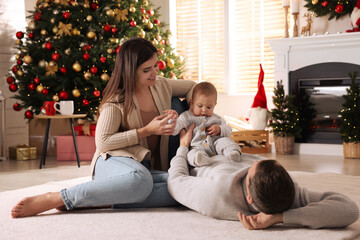 Poster - Happy family with cute baby on floor in room decorated for Christmas