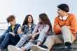 Beautiful, positive teenagers communicate happily with each other outdoors. Teenagers sit on a bench and talk.