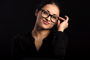 Wall Mural - Beautiful thinking smiling happy business woman  looking happy in eye glasses and holding spectacles in casual black t-shirt on black background with empty copy space. Closeup