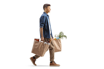 Wall Mural - Full length profile shot of a guy carrying grocery bags and walking
