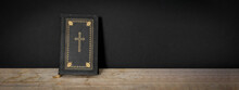 Church Faith Christian Background Banner Panorama - Old Holy Bible With Golden Cross On Old Rustic Vintage Wooden Table And Black Wall
