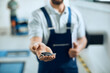 © Drazen - Close-up of mechanic holds car keys in auto repair workshop.