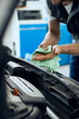 © Drazen - Close-up of mechanic wipes his dirty hands after working on car engine at repair shop.