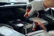 © Drazen - Close-up of mechanic uses  jumper cables while checking car battery in repair shop.