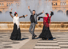 Three People With Flamenco Outfit Dancing In A Traditional Square