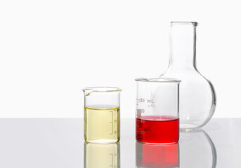 Cosmetic chemical ingredient on white laboratory table. Poly Aluminium chloride and Potassium Ferricyanide liquid in beaker place next to Flat Bottom Flask (Borosilicate Glass). Side View