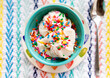 vanilla ice cream with rainbow sprinkles in turquoise bowl on colorful placemat