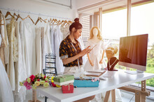 Small Business Of Asian Women Fashion Designer Working With Wedding Dresses At Clothing Store