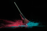 Fototapeta Konie - Blue and pink makeup powder brush fall on shiny black surface in a dust cloud