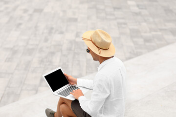 Poster - Handsome young man booking hotel room online on stairs outdoors