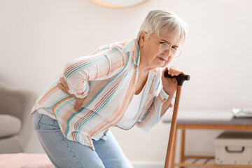 Sticker - Senior woman with walking stick suffering from back pain in bedroom