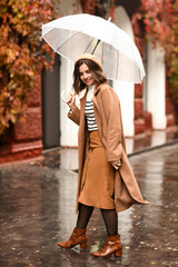 Poster - Young happy woman with umbrella walking on rainy autumn day