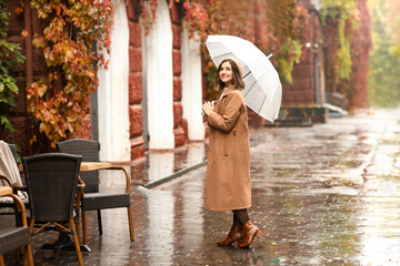 Sticker - Smiling woman with umbrella on rainy autumn day