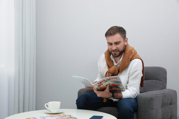 Sticker - Handsome man reading magazine in armchair at home