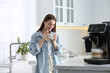 © New Africa - Young woman enjoying fresh aromatic coffee near modern machine in kitchen