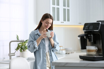 Poster - Young woman enjoying fresh aromatic coffee near modern machine in kitchen