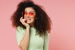 © ViDi Studio - Confused preoccupied worried young curly latin woman 20s years old wears mint t-shirt sunglasses biting fingertips nails looking aside isolated on plain pastel light pink background studio portrait.