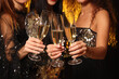 © New Africa - Women with glasses of sparkling wine celebrating New Year on black background, closeup