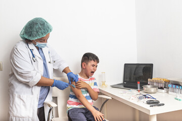 Vaccination concept. Female doctor vaccinating cute little boy on blue background, closeup.