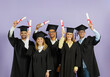 © Studio Romantic - Congrats, grad. Happy proud smiling joyful diverse international university students in graduate caps and gowns raise up paper diplomas with red ribbon standing on color background at graduation event