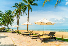 Beautiful Tropical Beach And Sea With Umbrella And Chair Around Swimming Pool In Hotel Resort