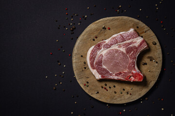 Wall Mural - Pork meat on a black background. Meat loin with bone on a wooden board. Meat cooking