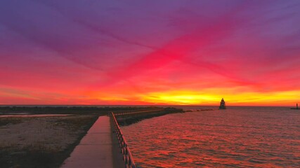 Wall Mural - Incredibly colorful, dramatic sunrise sky over Lake Michigan harbor and lighthouse moving aerial view.