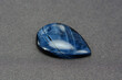 Natural pietersite microcrystalline quartz. Deep saturated blue color veins drop shaped loose cabochon gemstone setting ready for making jewelry. Gray background. Gemology, mineralogy theme.