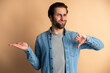 Man in shirt criticizing bad quality with thumbs down displeased grimace, showing dislike gesture