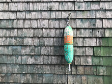 Close-up Of A Colorful Lobster Buoy On A Gray Wooden Shingled Background In Maine, USA