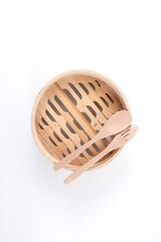 A Bamboo Steamer Basket With Wooden Fork And Spoon