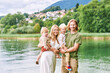 © annanahabed - Outdoor portrait of beautiful family, young couple with preschooler boy and toddler girl posing next to lake or river