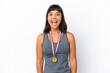 © luismolinero - Young mixed race woman with medals isolated on white background with surprise facial expression