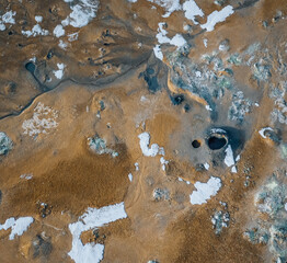 Wall Mural - Aerial Drone panorama with hot steam coming from the ground. Hverir is geothermal area in Myvatn. Landscape covered with snow and orange ground.