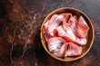 Smoked sliced bacon in wooden plate. Dark background. Top view. Copy space