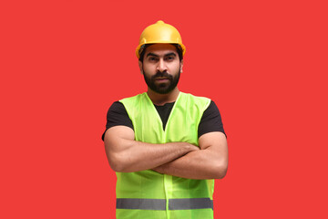 young construction worker wearing safety vest and standing with folded hand indian pakistani model