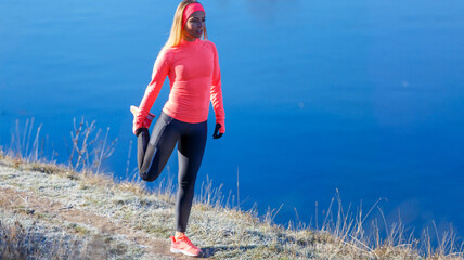 Young sporty woman stretching her legs in the frosty morning before running