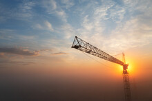 Construction Cranes At Dawn In The Morning Mist.