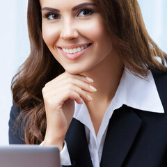 Wall Mural - Portrait image of happy smiling attractive business woman in black confident suit working with laptop computer at office. Success in business, job and education concept. Square.