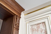 Decorated Wooden Doorway With Carved Furniture Brackets And Fluted Panel And Vintage Wall Panel With Golden Molding In Classic Style Closeup