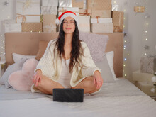 Beautiful Woman Sitting On Bed Working With Laptop At Home Around Christmas Lights Relax And Smiling With Eyes Closed Doing Meditation. Yoga Concept.