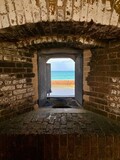 Fototapeta Do przedpokoju - Fort Jefferson, Dry Tortugas National Park, Florida Keys. Looking out from the brick fort. Window with Totten Shutters. Moat wall, or counterscarp, and Gulf of Mexico turquoise water. 