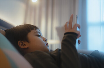 Wall Mural - Kid reading bed time stories on tablet before sleep, Happy boy lying in bed playing games on digital pad, Portrait Child relaxing at home in his bed room on weekend.