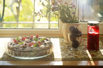 Sticker - bouquet of summer flowers and berry pie with fresh raspberries, currants, mint and cream close-up on a windowsill in a private house