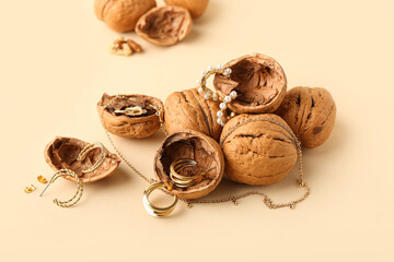 Stylish golden jewelry and walnuts on color background