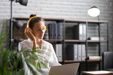 Wall Mural - Pretty young woman with laptop listening to music at home