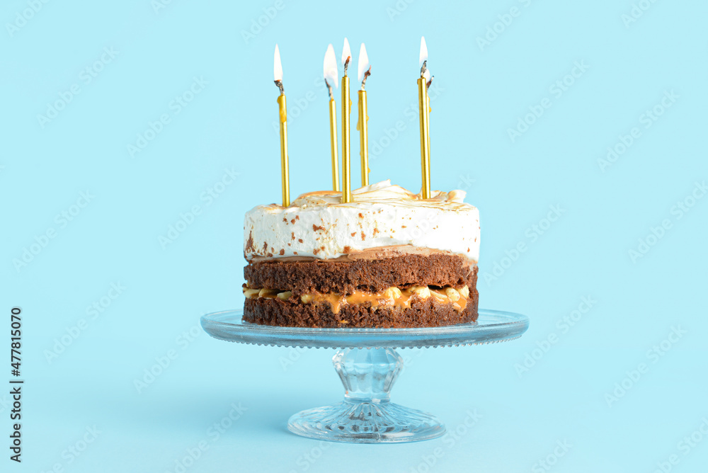 Stand with tasty birthday cake and burning candles on blue background