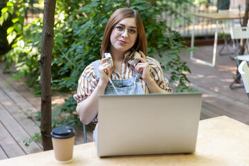 Wall Mural - Young pretty woman with laptop and headphones in outdoor coworking space