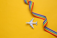 Toy Passenger Plane With Lgbt Rainbow Ribbon On Yellow Background