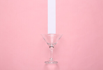 Wall Mural - Cocktail empty glass on pink pastel background with white stripe. Minimalism. Top view